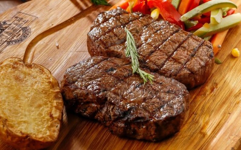 Trình bày món bít tết sốt bơ tỏi ra đĩa và dùng kèm rau xanh